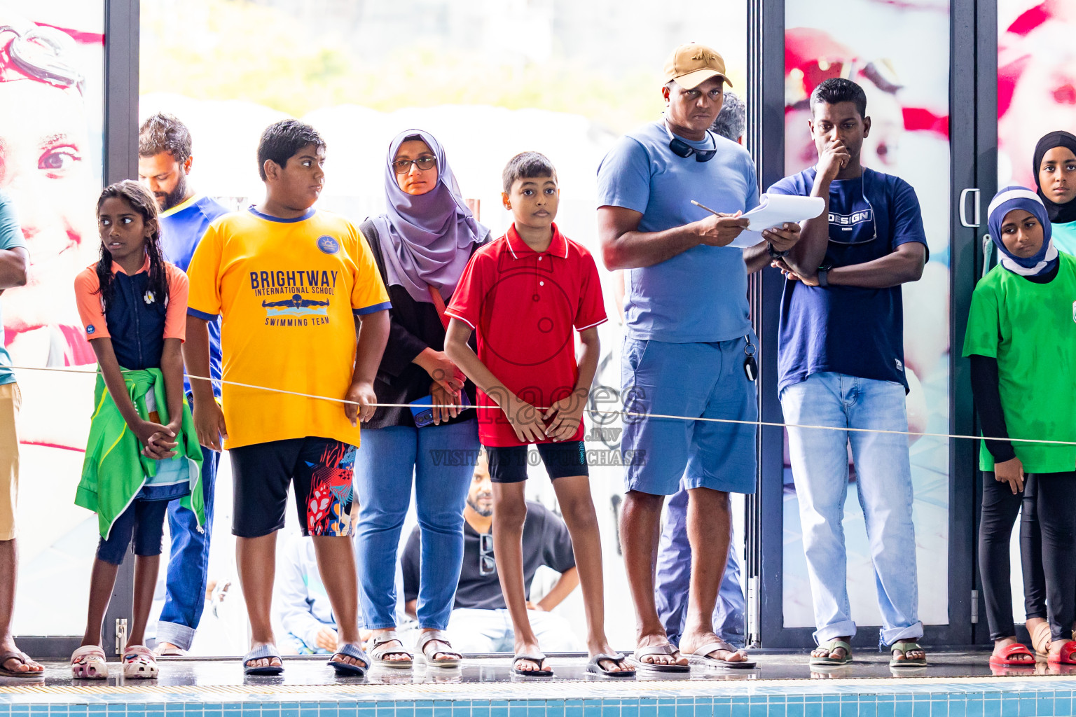 group of students standing next to a swimming pool with their swimming coach
